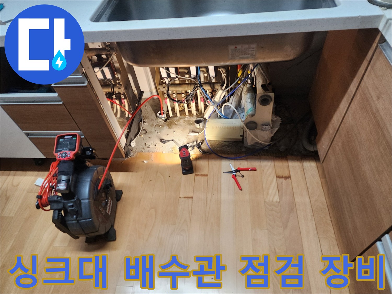 싱크대 밑 배수 호스와 관통기 장비가 배치된 현장 모습
