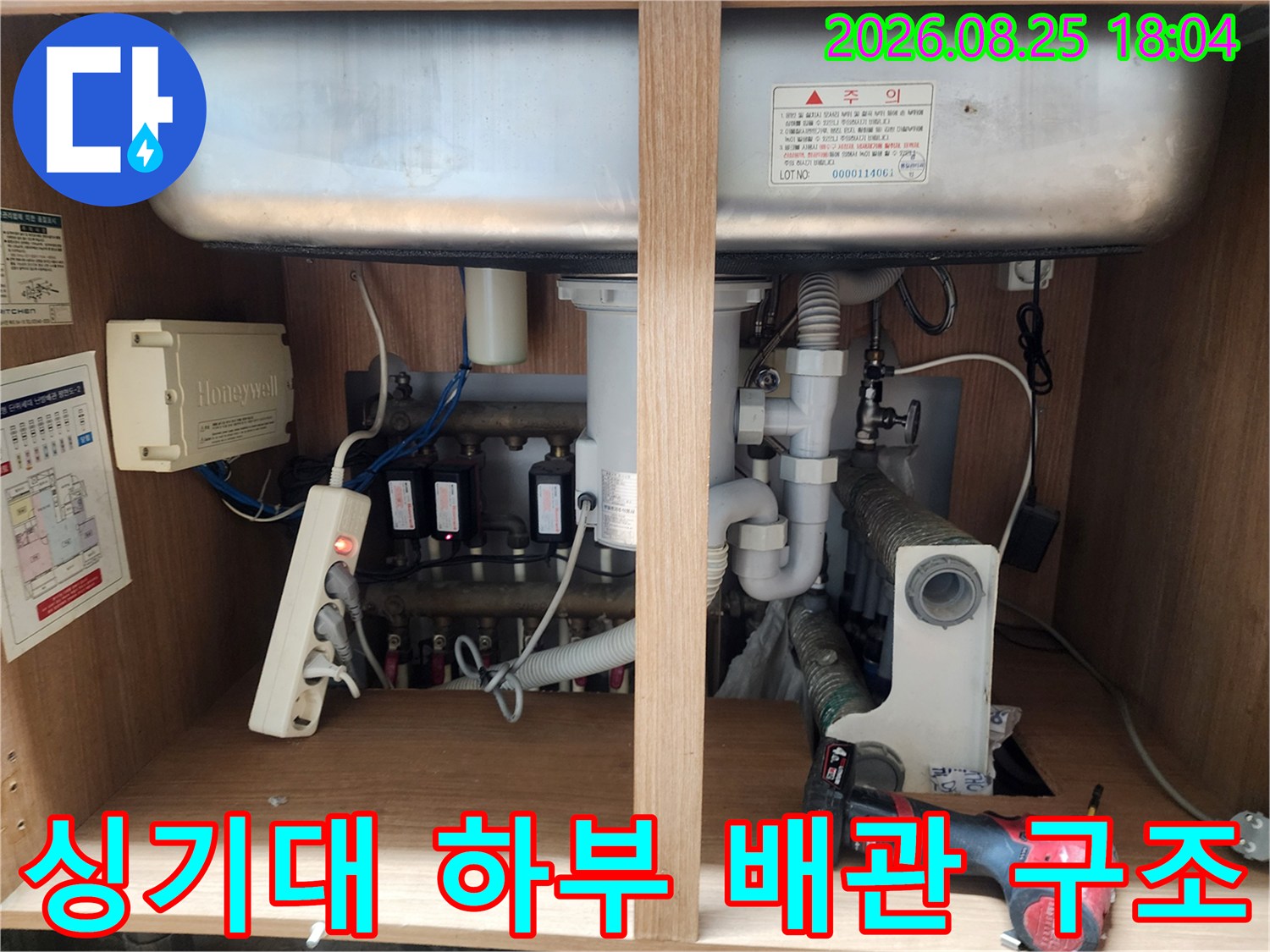싱크대 아래쪽의 복잡한 배관 밸브와 호스 연결 상태 점검