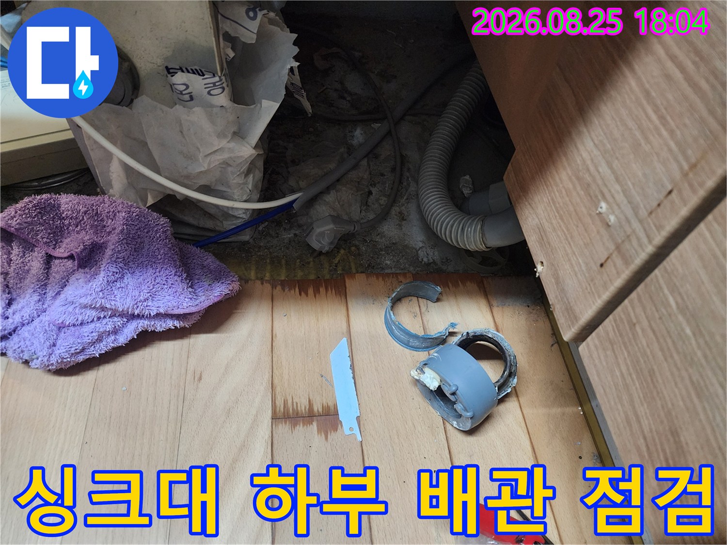 싱크대 하부장 내부의 노출된 배수 배관과 분리된 부속품 상태