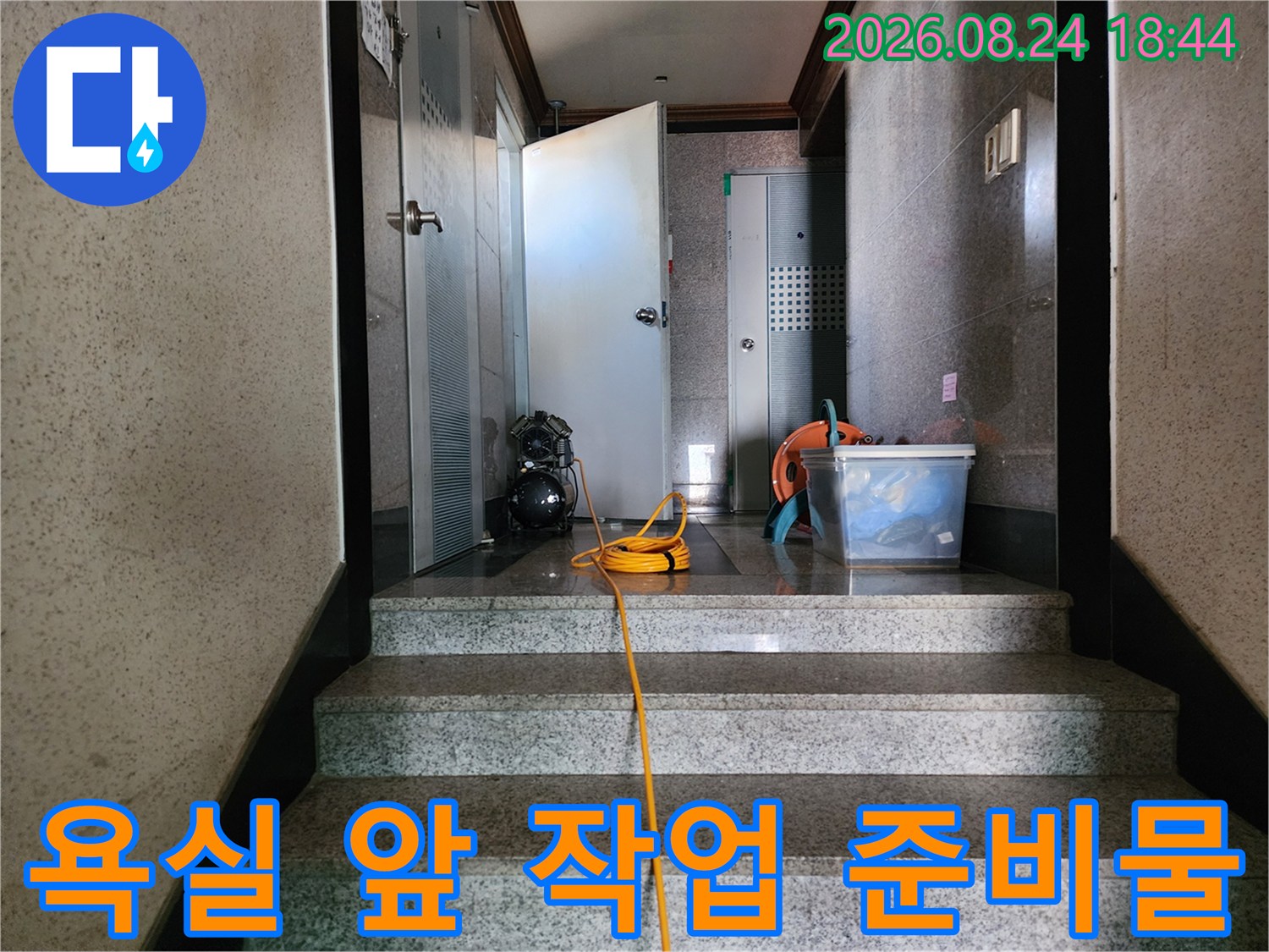 화장실 입구 바닥-누수 점검을 위해 세팅된 전선과 청소 도구