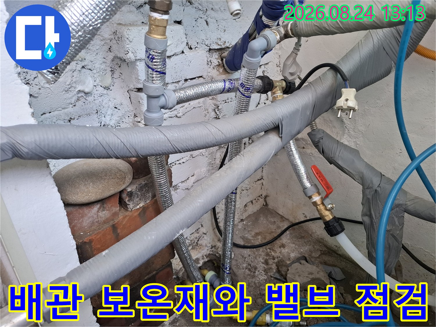 회색 단열재로 감싸진 배관과 금속 밸브가 보이는 설비 현장 사진입니다.
