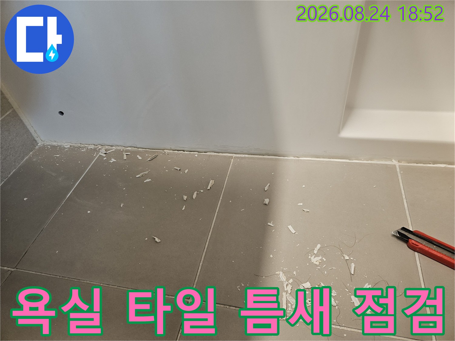 타일 사이의 파편과 벽면 경계의 균열 상태를 촬영한 사진