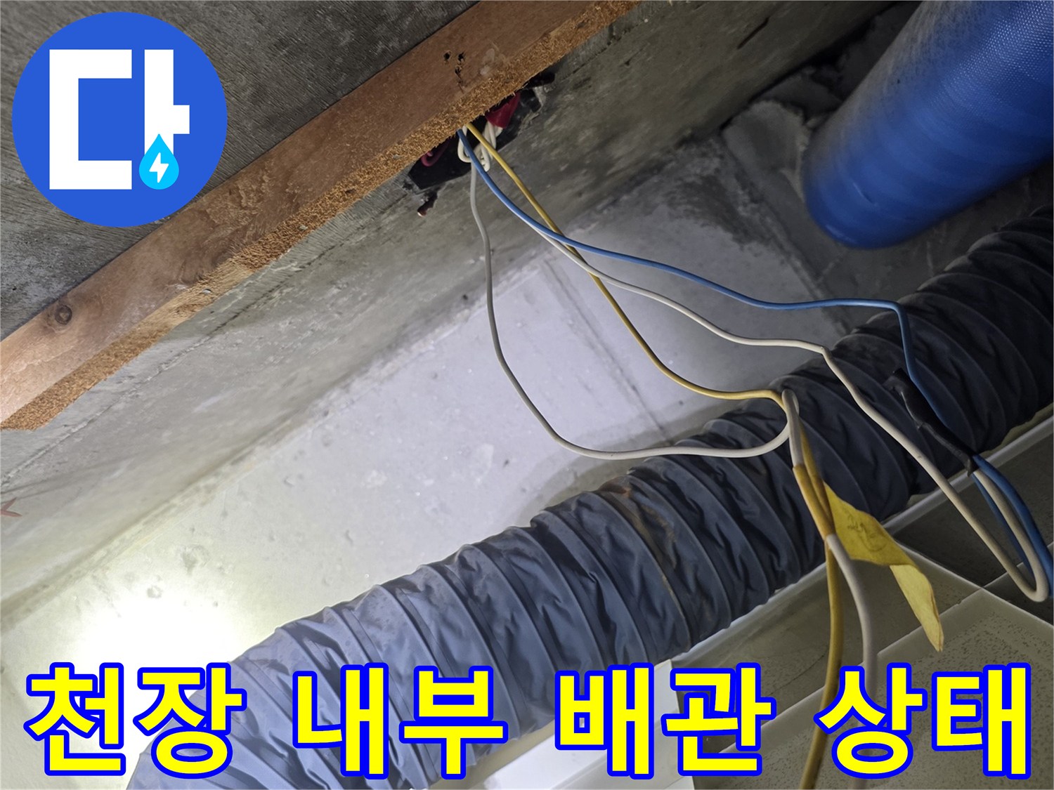 천장 구조물 사이로 보이는 노후된 배관과 전기 배선 점검 중인 사진