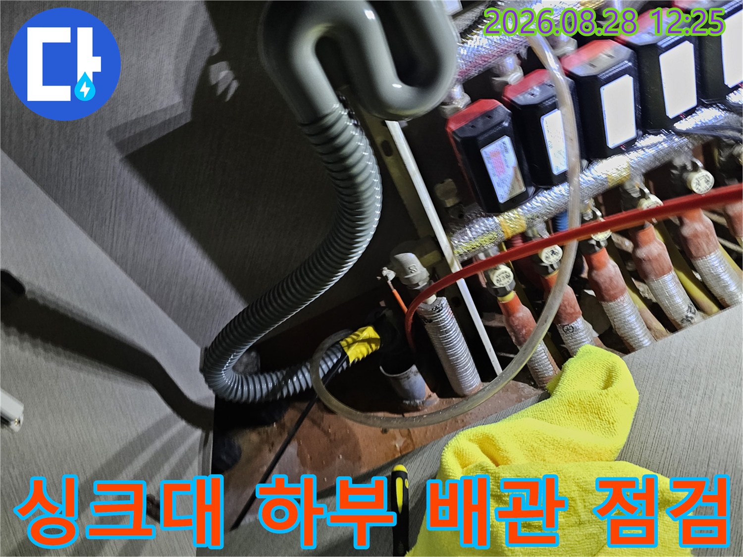싱크대 밑 공간에 노출된 보일러 분배기와 각종 급수 배관의 모습입니다.