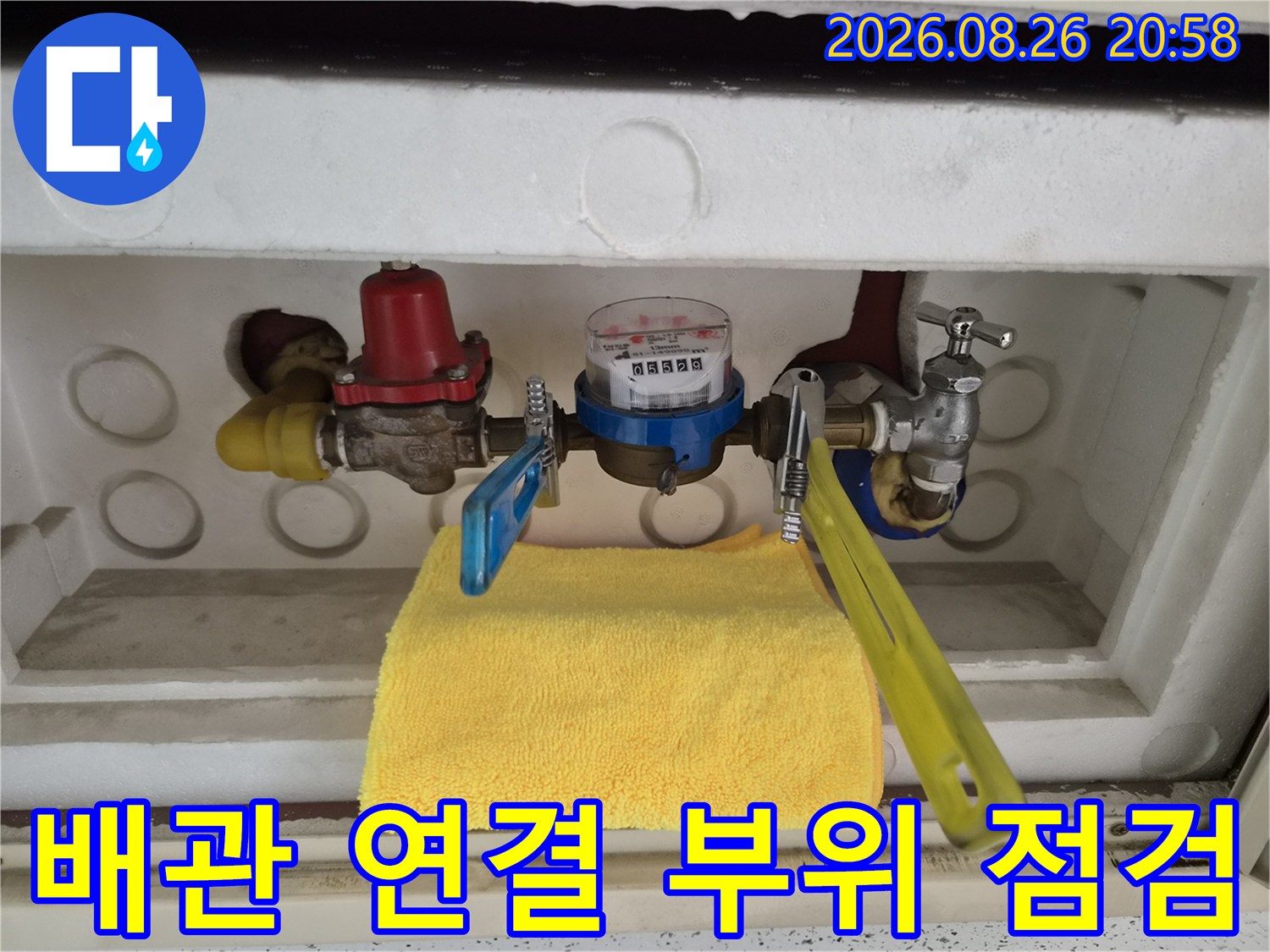 수도 계량기 함 내부에 설치된 금속 배관 및 밸브 장치입니다.
