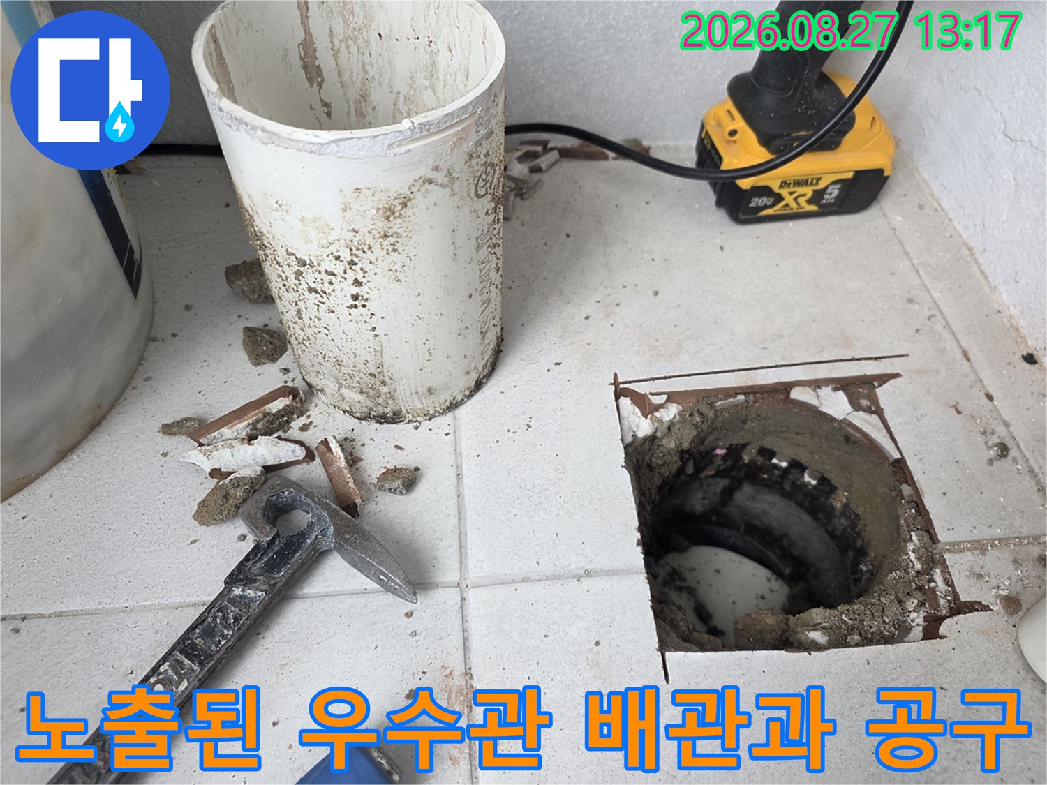 우수관 주변의 굴착된 바닥과 작업용 전동 드릴 및 망치가 놓여 있는 누수 공사 현장입니다.
