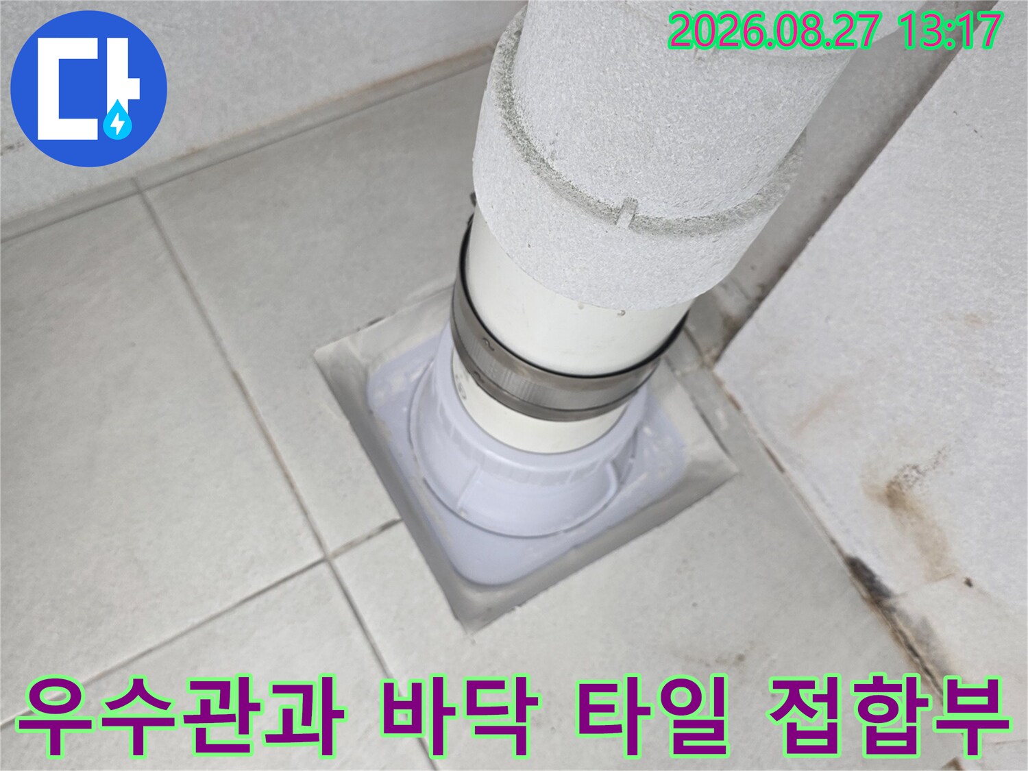 타일 바닥에 설치된 우수관 배관의 연결 부위 상세 사진