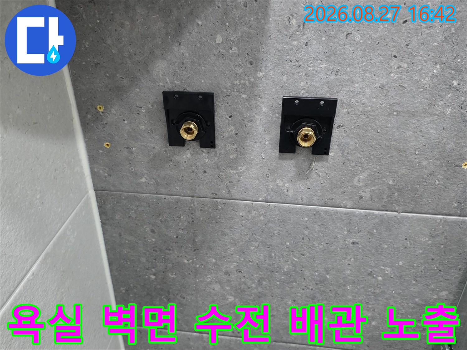 회색 타일 벽면에 드러난 샤워기 수전용 황동 배관 연결부