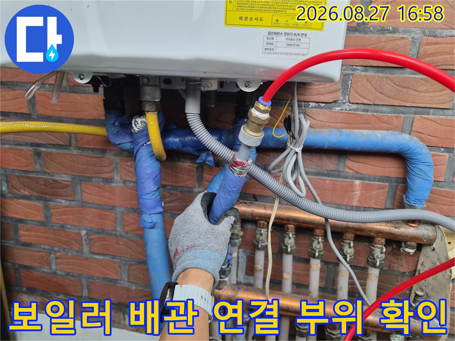 파란색 보온재가 감긴 배관과 금속 부품을 점검하는 작업자의 손