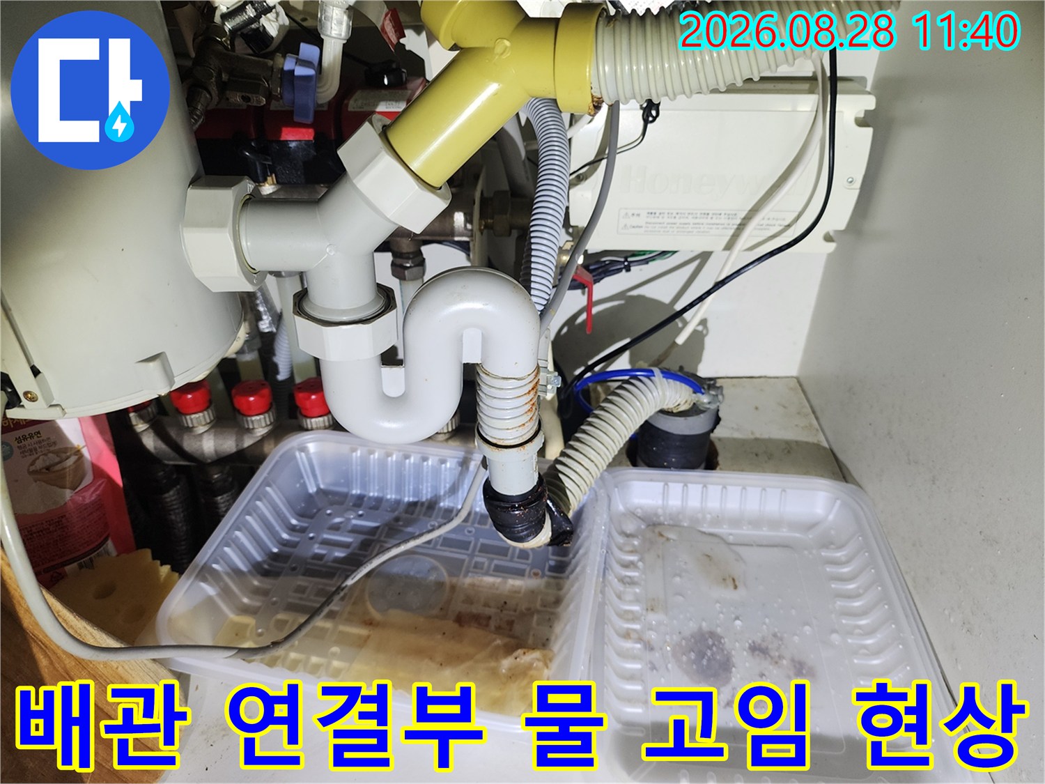 배수 트레이에 물이 고여 있는 싱크대 하부 배관 연결 부위 모습