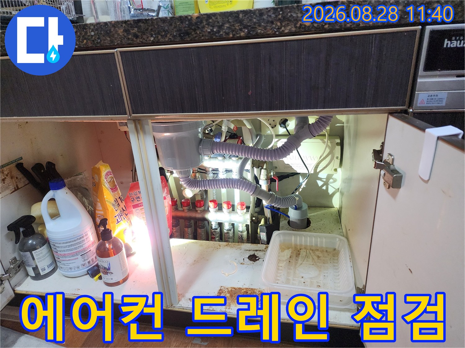 싱크대 하단 내부의 에어컨 드레인 호스와 연결된 배관 부위 상세 사진