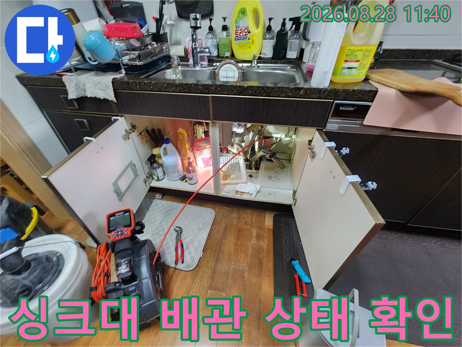 싱크대 하부장 내부의 복잡한 배관 구조와 누수 측정 장비