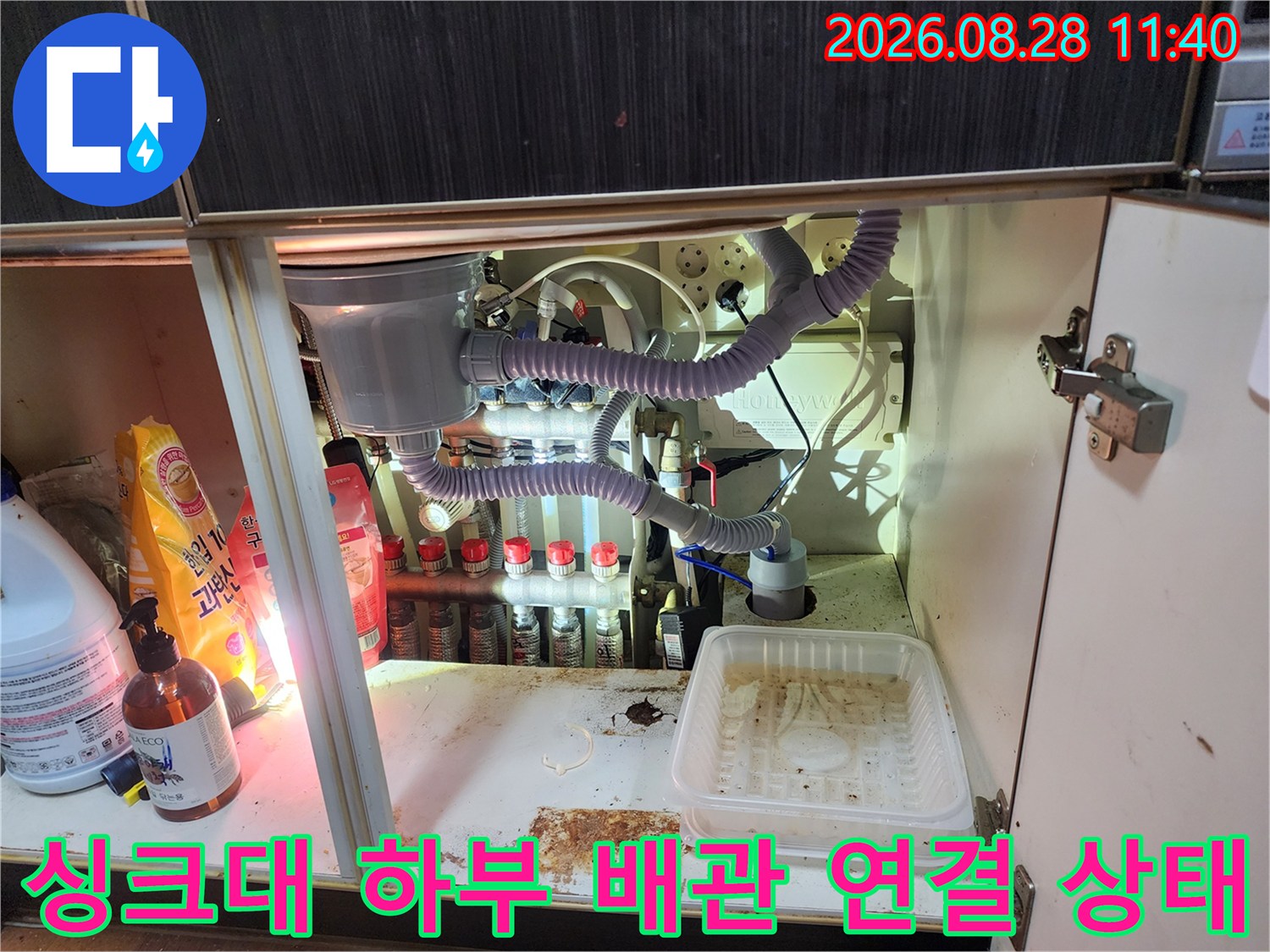 정수기 필터와 에어컨 호스가 복잡하게 연결된 싱크대 내부