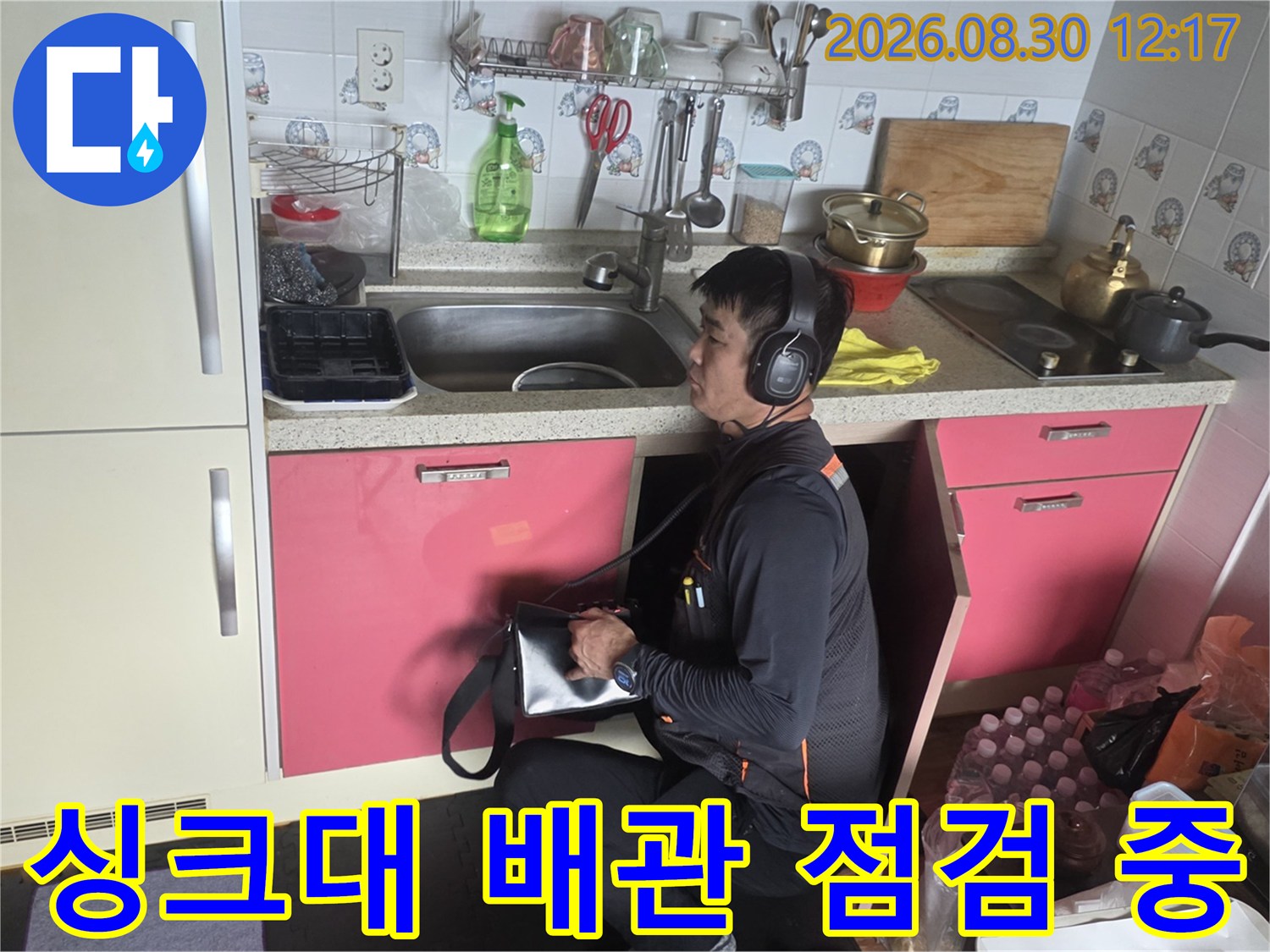주방 싱크대 밑에서 누수 지점을 찾는 전문적인 탐지 작업 모습입니다.