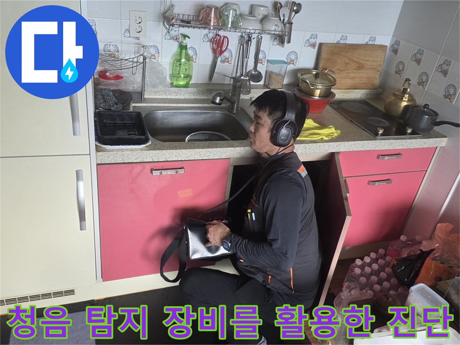 헤드셋 형태의 청음기를 사용하여 주방 배관의 소리를 듣는 모습