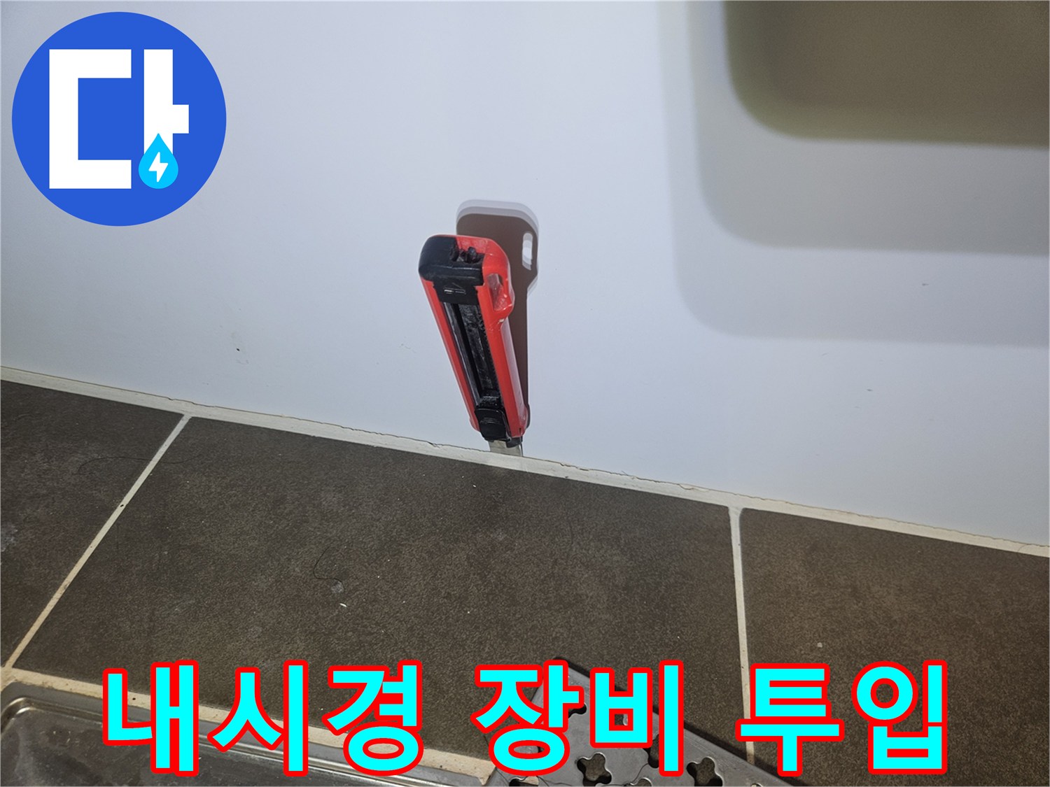 타일 벽면에 뚫린 구멍에 삽입된 내시경 카메라와 주변 타일 모습