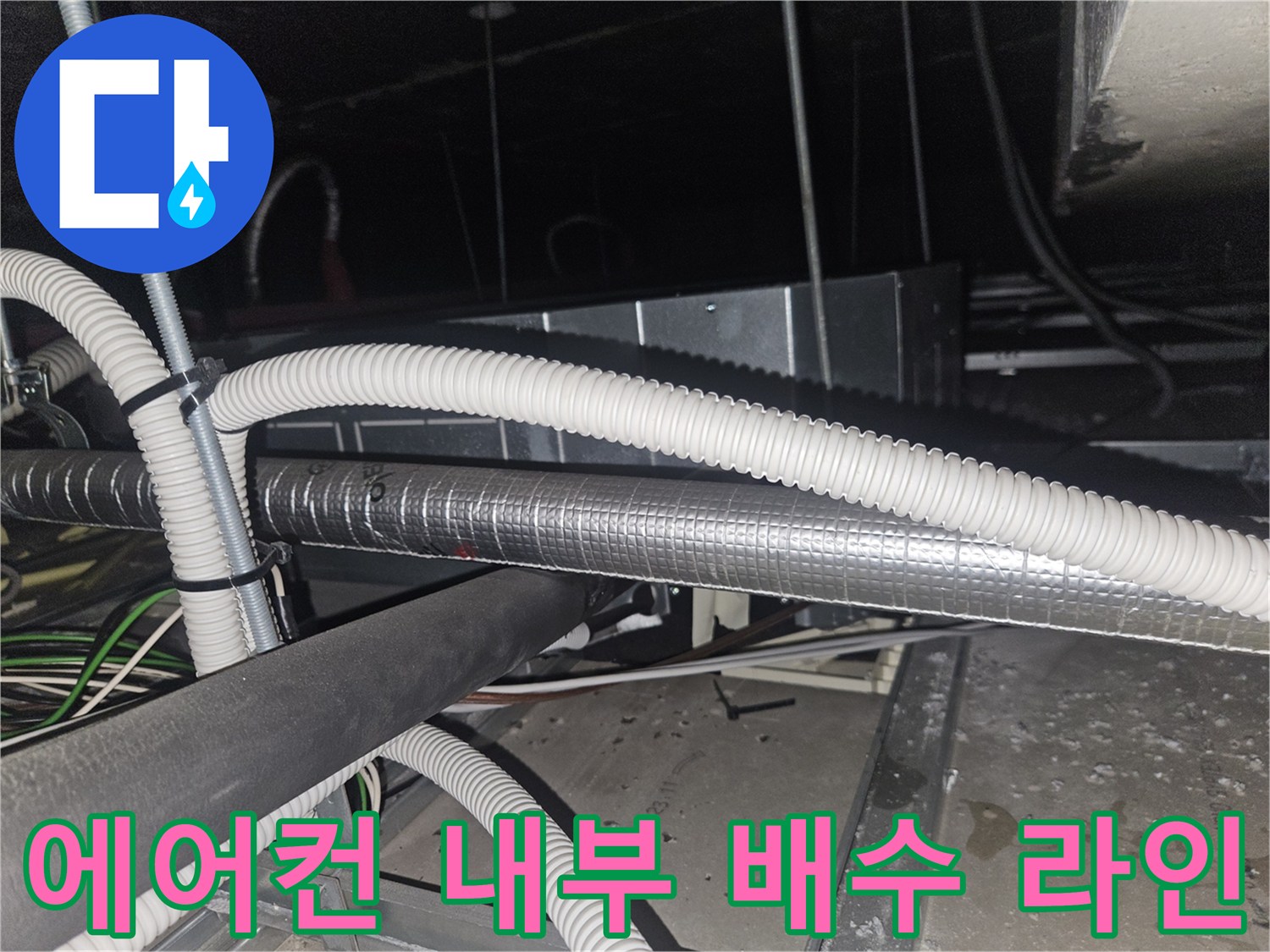 천장 텍스 사이로 보이는 은색 보온재와 흰색 주름 배관 구조