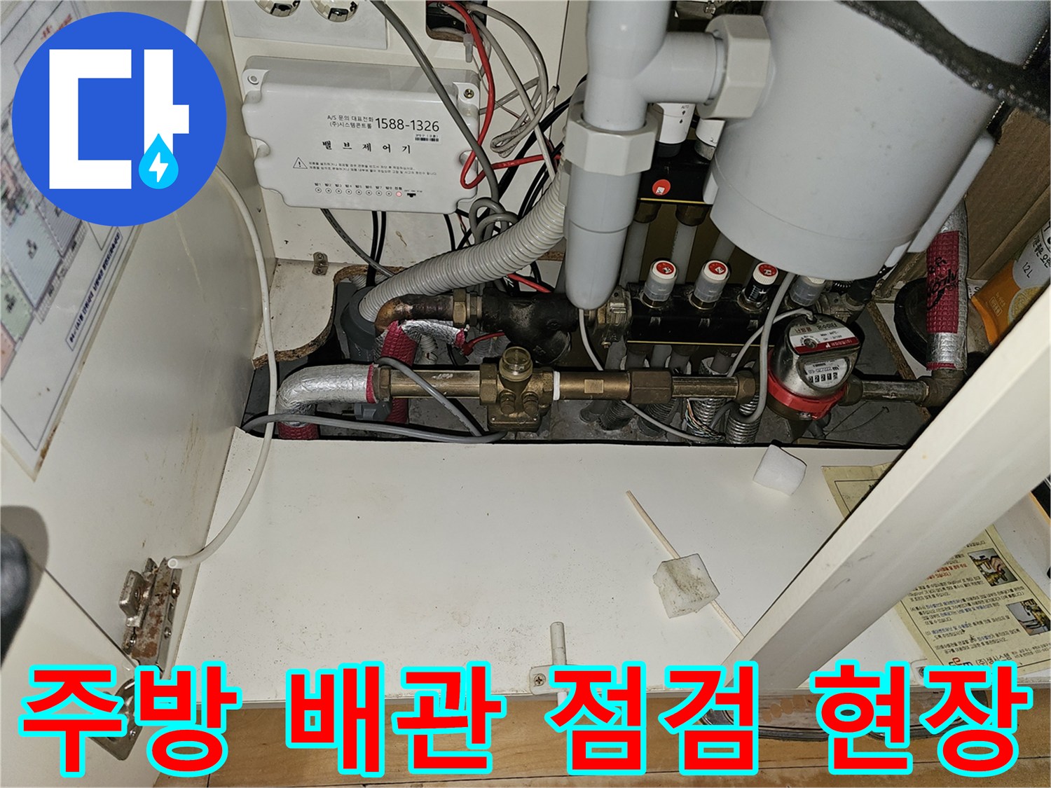 분당 백현동 아파트 주방 하부장 내부의 난방 분배기와 연결된 금속 배관 모습
