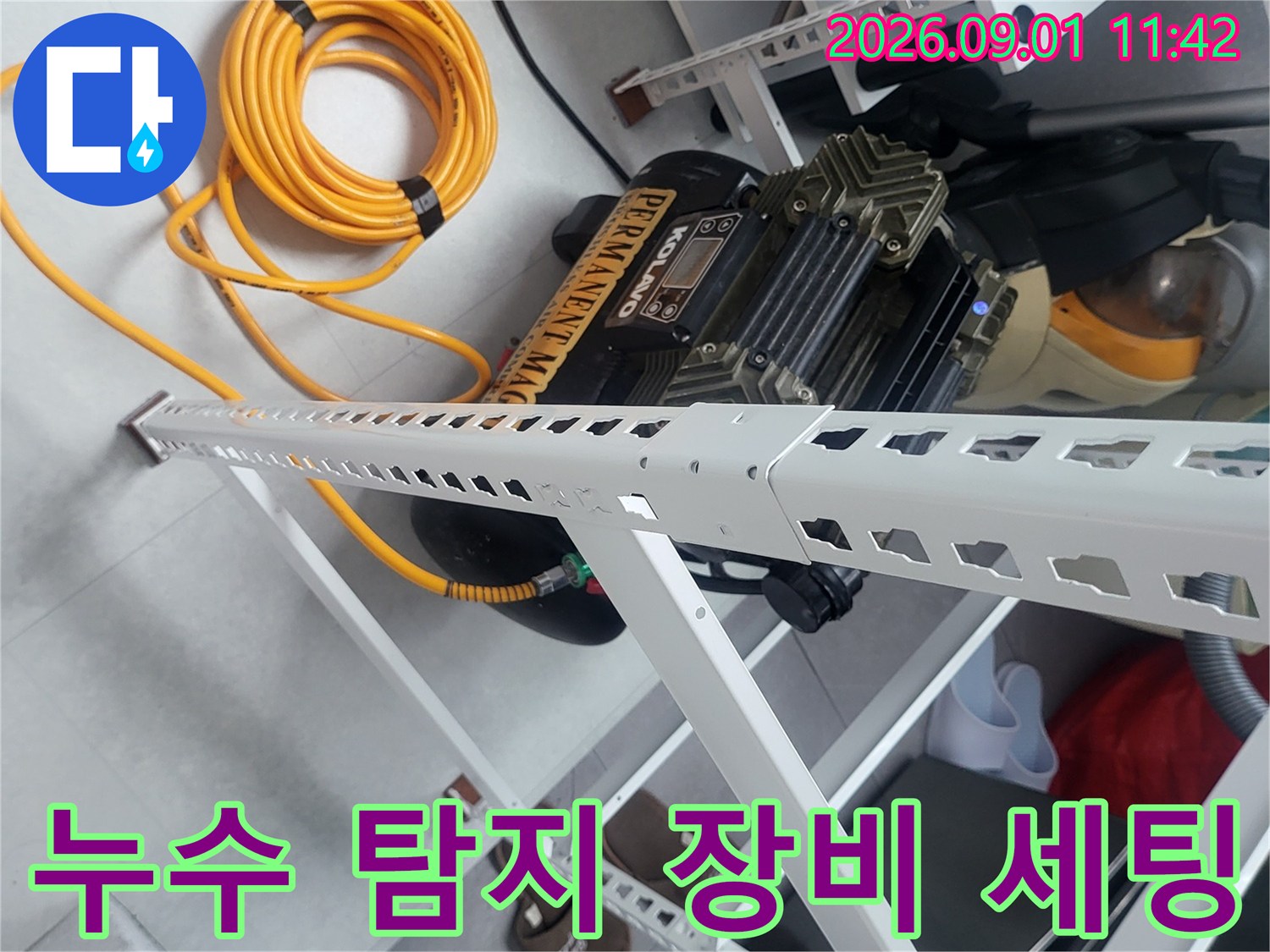 화이트 랙 선반 아래 놓인 검은색 공압 압력계와 노란색 호스 연결 상태