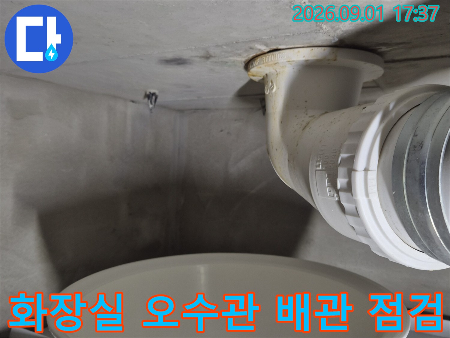 화장실 천장에 노출된 하얀색 오수관과 연결 부위 모습입니다.