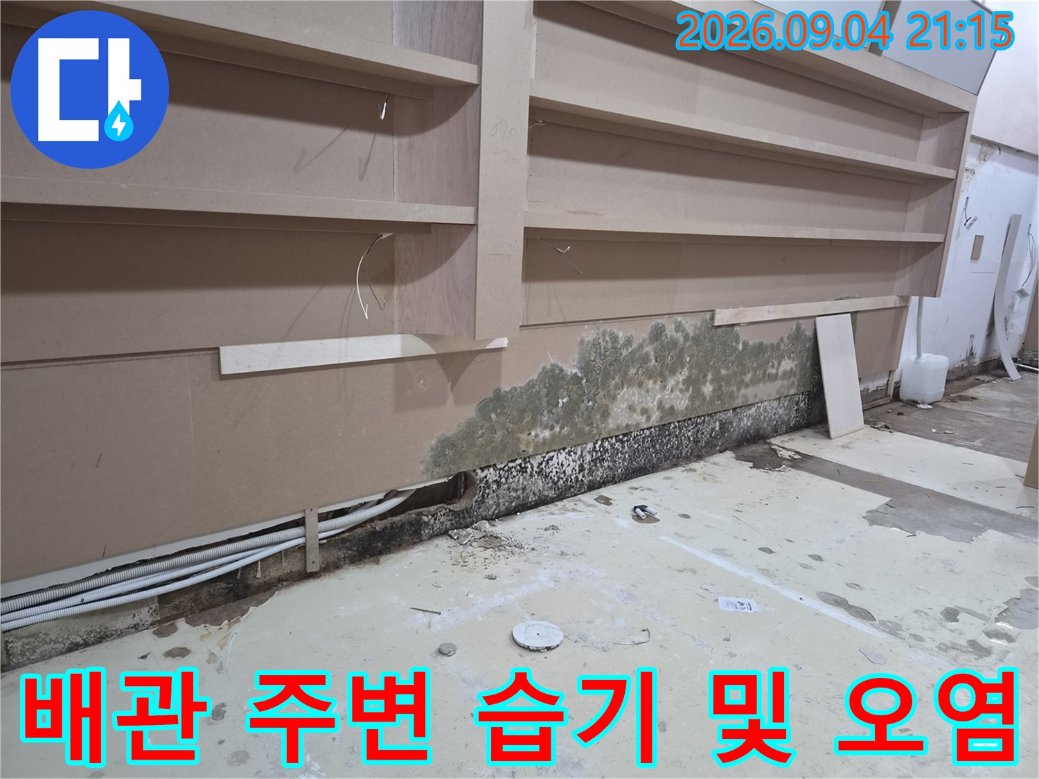 노출 배관 하단부의 젖은 벽면과 곰팡이 발생 부위