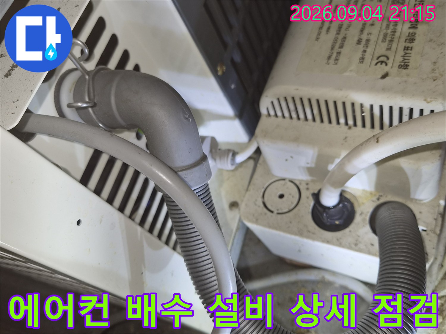 상가 내부 에어컨 하단부의 배수 호스와 전기 장치 연결 상태를 보여줍니다.