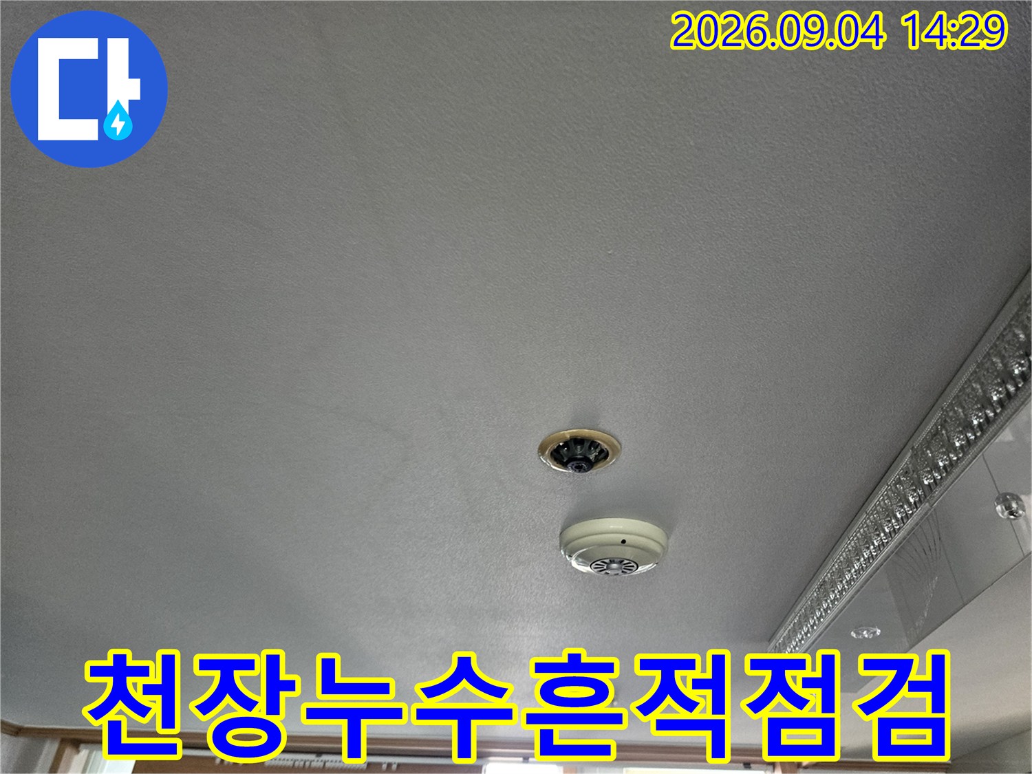 거실 천장의 소방 감지기와 조명 기구가 설치된 마감면 상태입니다.