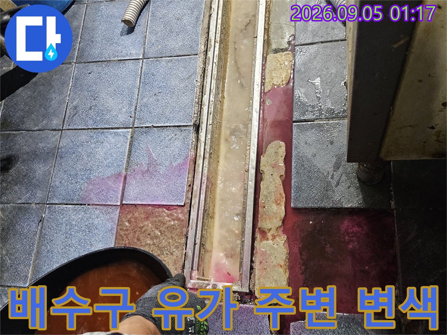 트렌치 금속 프레임 주변의 붉은 얼룩과 노후된 타일 줄눈 상태를 촬영한 이미지입니다.
