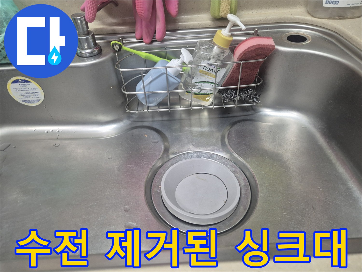 수전이 탈거되어 배관 입구가 보이는 스테인리스 싱크대 내부 모습입니다.