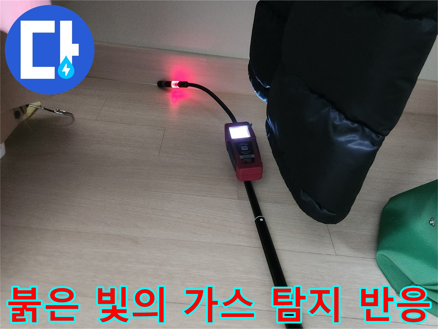 가스 탐지기가 붉게 빛나며 옷방 구석 배관 누수를 가리키고 있는 사진입니다.