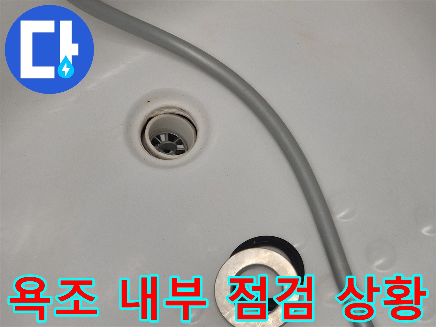 배수구와 점검구가 노출된 욕조 하부 모습