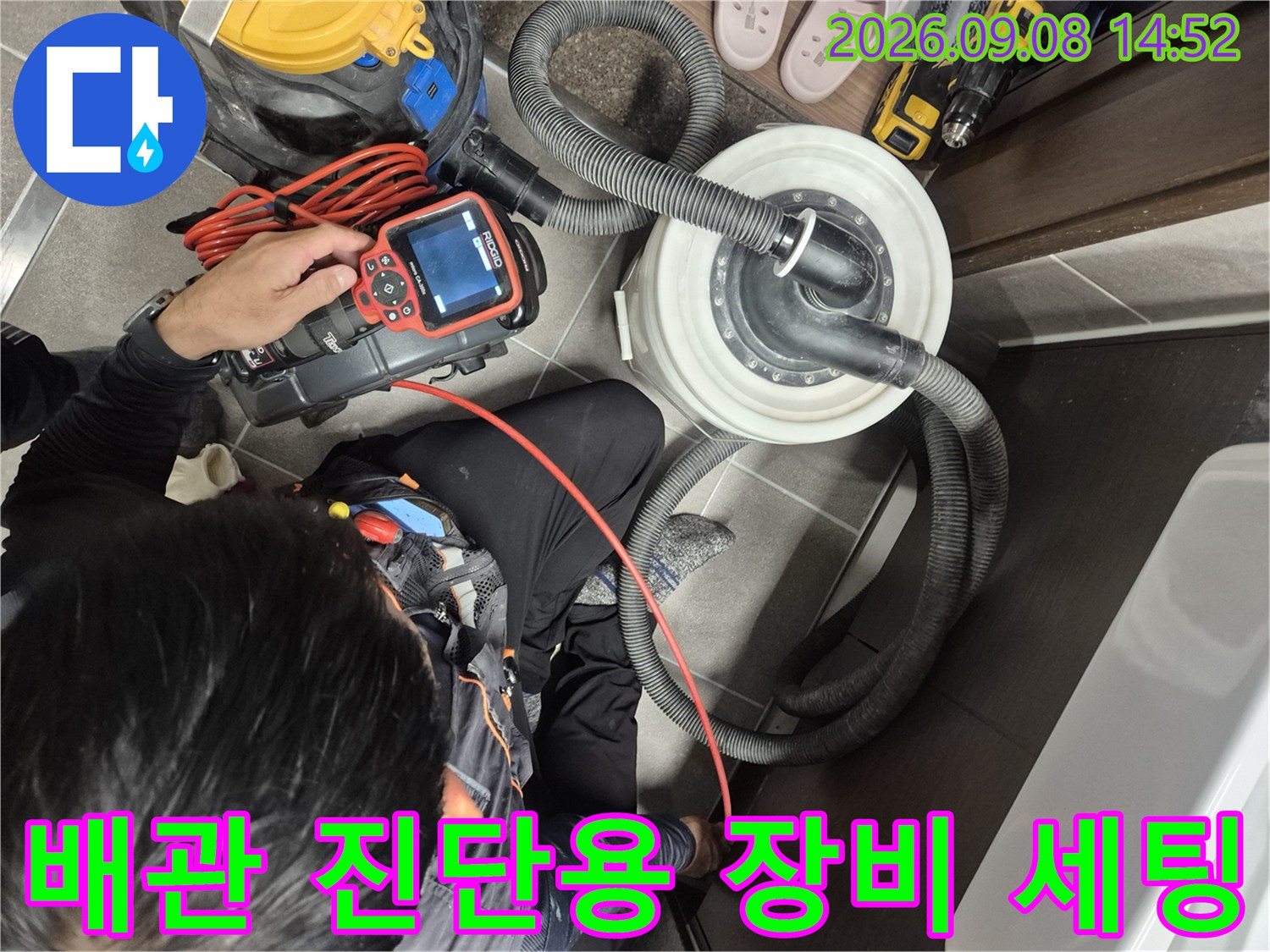 누수 탐지를 위해 배관과 연결된 굵은 호스와 탐지기 장비를 준비하는 모습입니다.