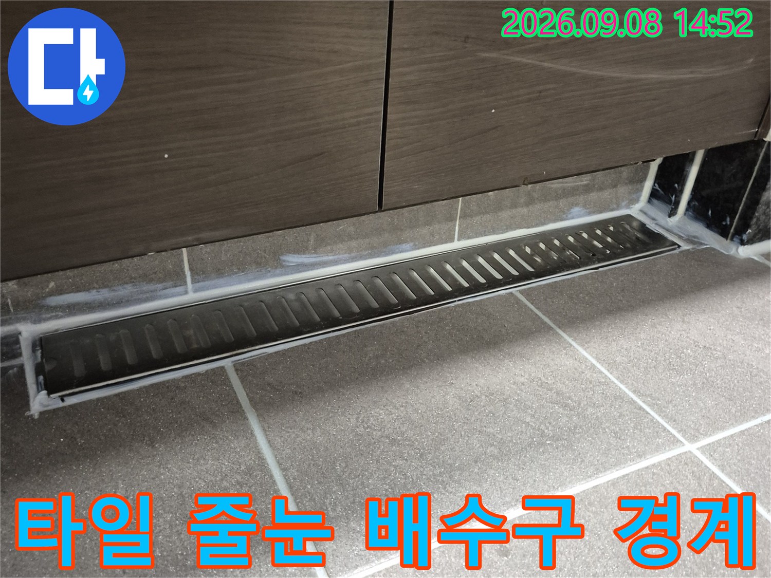 타일 줄눈과 배수구 유가 사이의 연결 부위를 찍은 사진입니다.