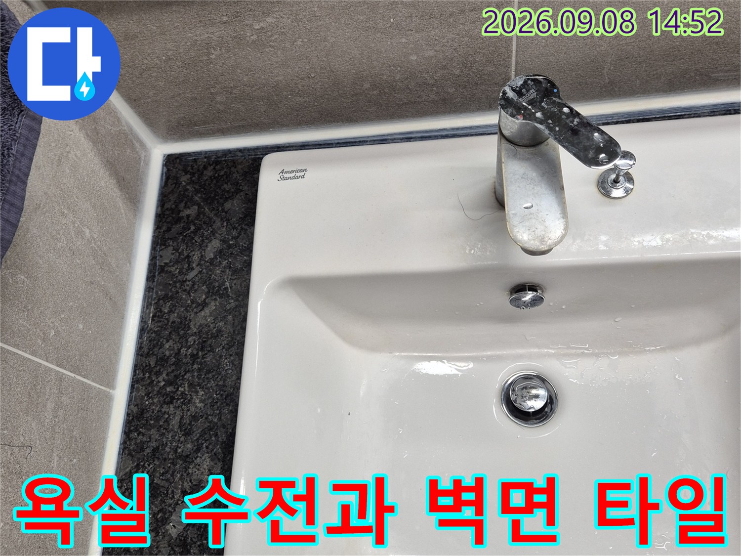 회색 타일 벽면에 설치된 은색 수도꼭지 근접 사진