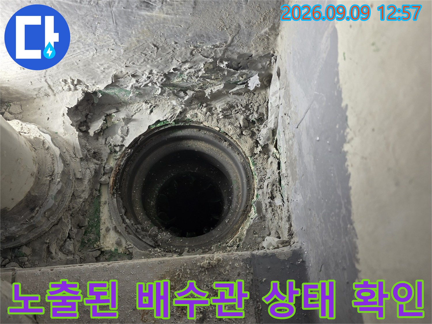 기존 마감재를 제거하여-드러난 배수관과 주변의 파손된 시멘트 모습입니다.