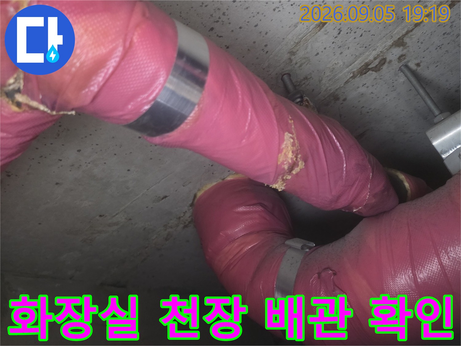 점검구 내부-분홍색 보온재가 씌워진 배관의 노출된 상태를 보여줍니다.