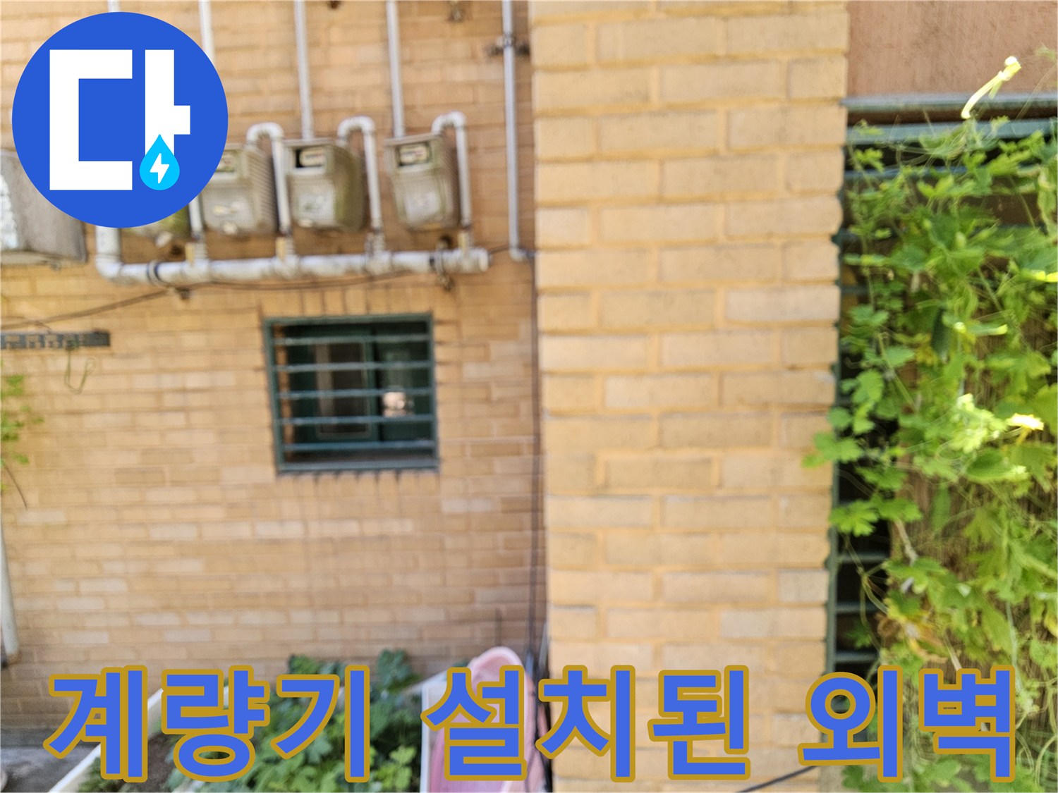 황색 벽돌 건물 외벽에 배치된 수도 계량기 시설물입니다.