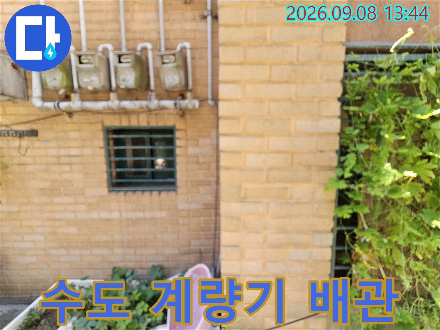 벽돌 벽면에 설치된 여러 개의 수도 계량기와 연결 배관 사진입니다.