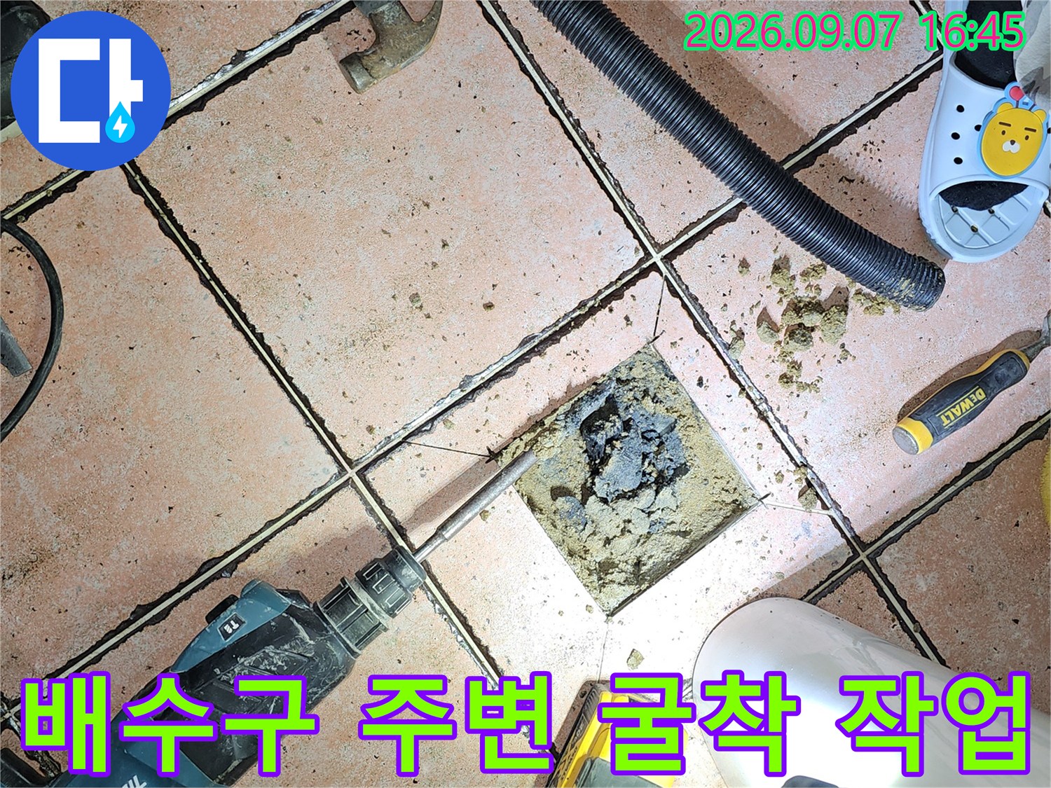 화장실 배수관 주변의 타일을 제거하고 내부를 정리하는 공사 현장입니다.
