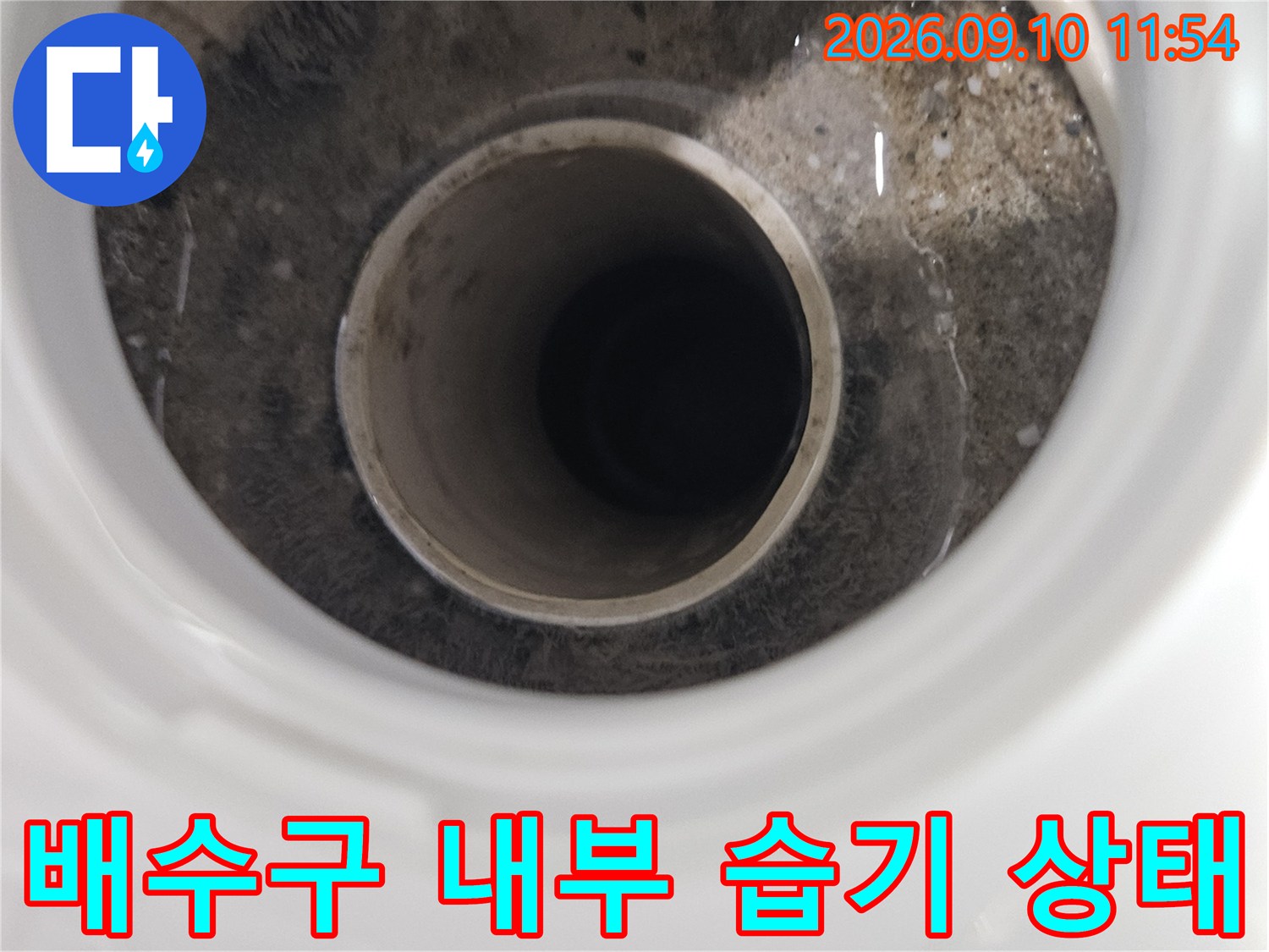 배수구 배관 주변의 젖은 흔적과 오염된 마감재를 보여줍니다.