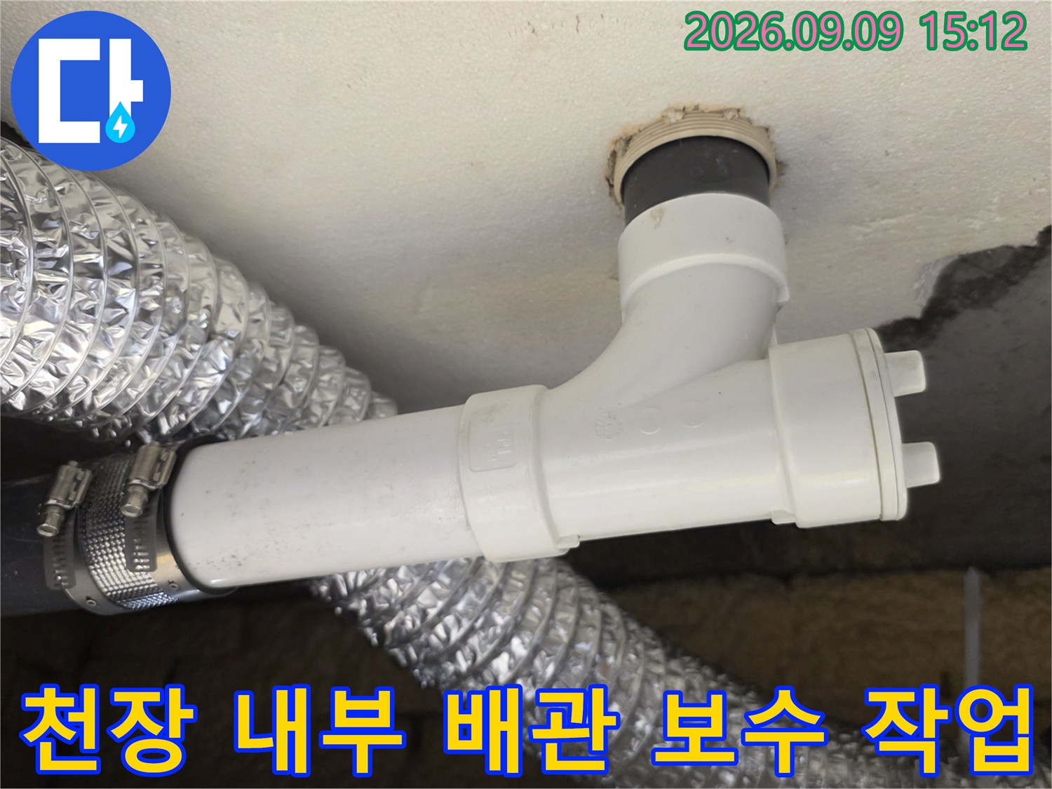 천장 슬래브에 연결된 흰색 PVC 하수관과 은색 보온재로 감싸진 배관의 모습