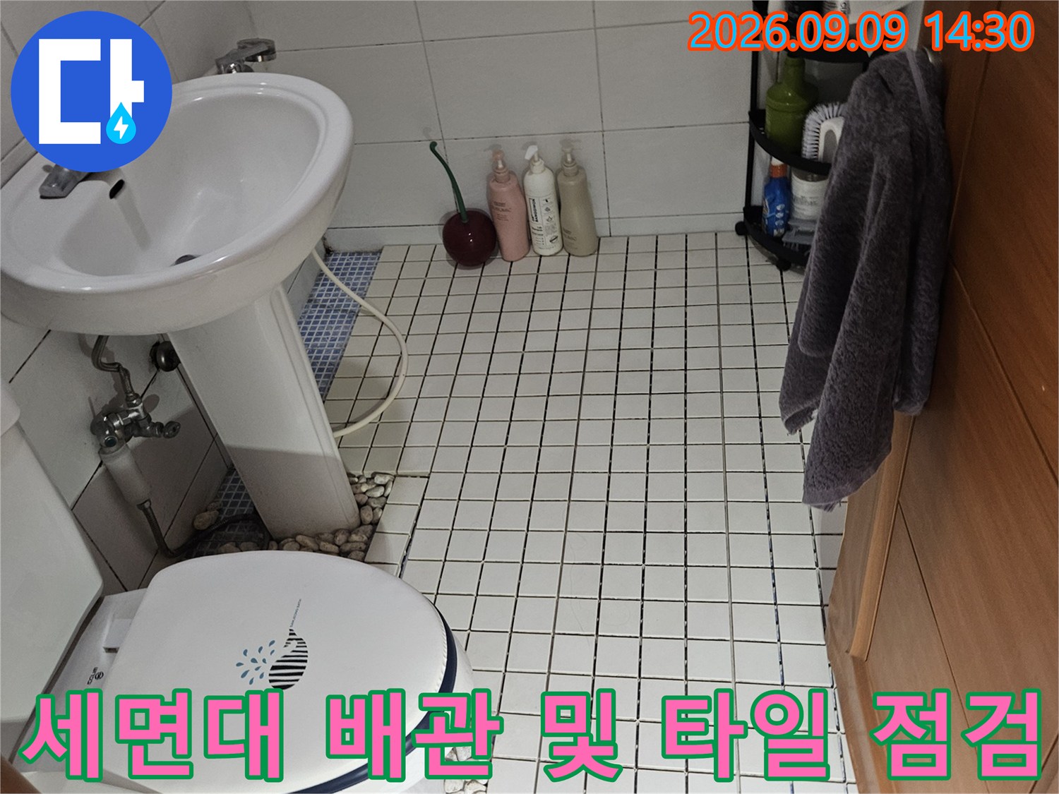 석촌동 욕실 벽면-타일과 세면대 하부 배관의 상태를 촬영한 사진입니다.