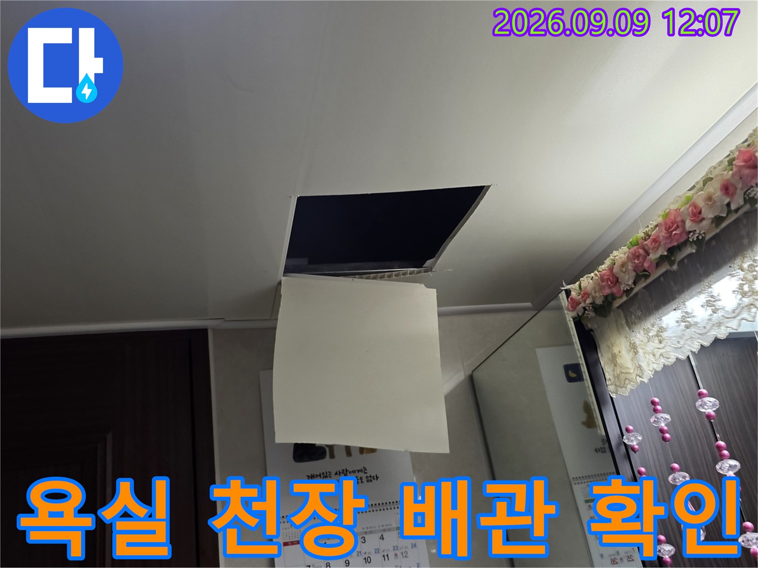점검구를 통해 욕실 천장 내부의 배관 연결 부위를 점검하고 있습니다.