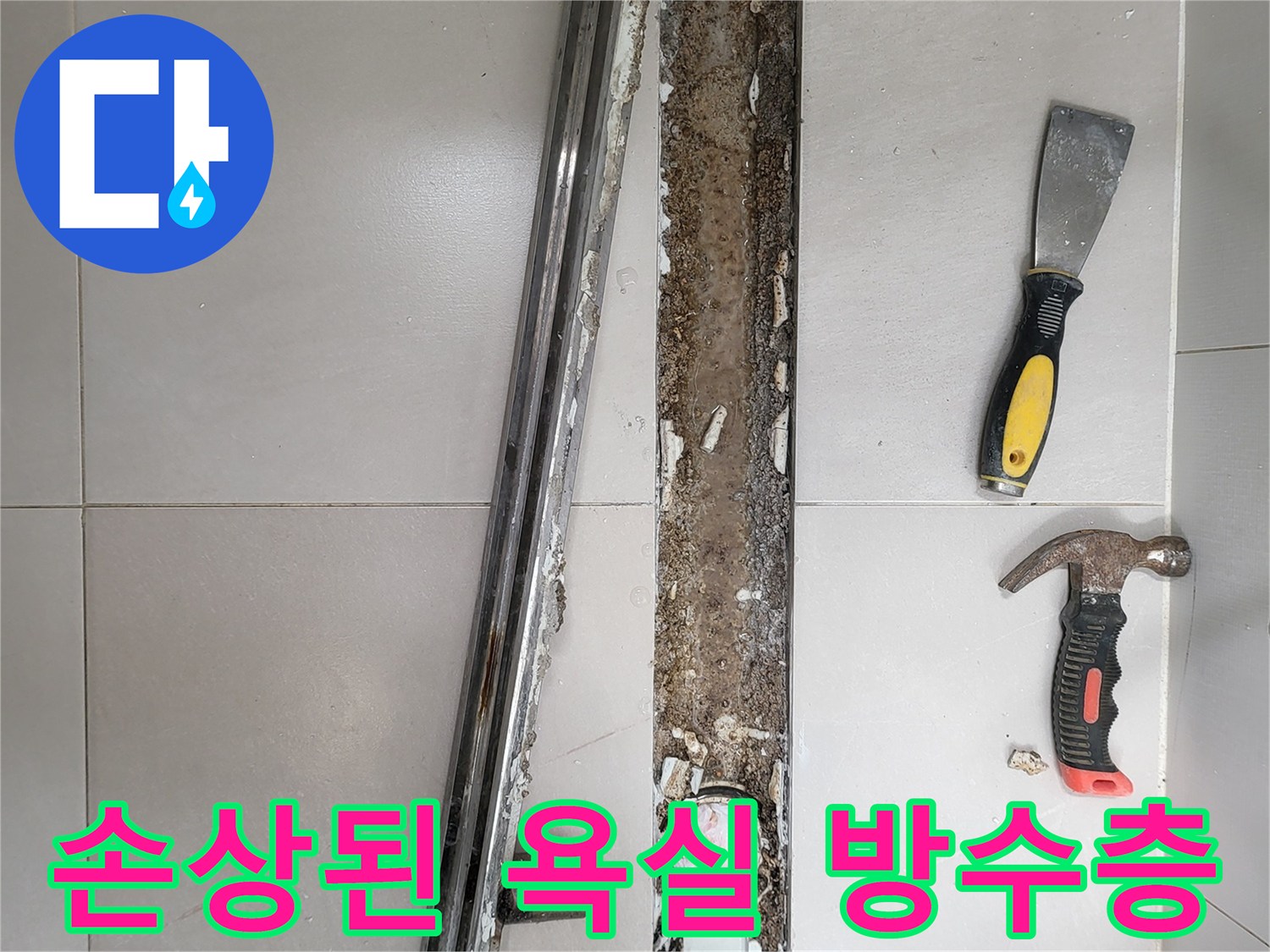 타일 아래쪽 배수구 주변의 훼손된 방수층과 작업 도구들