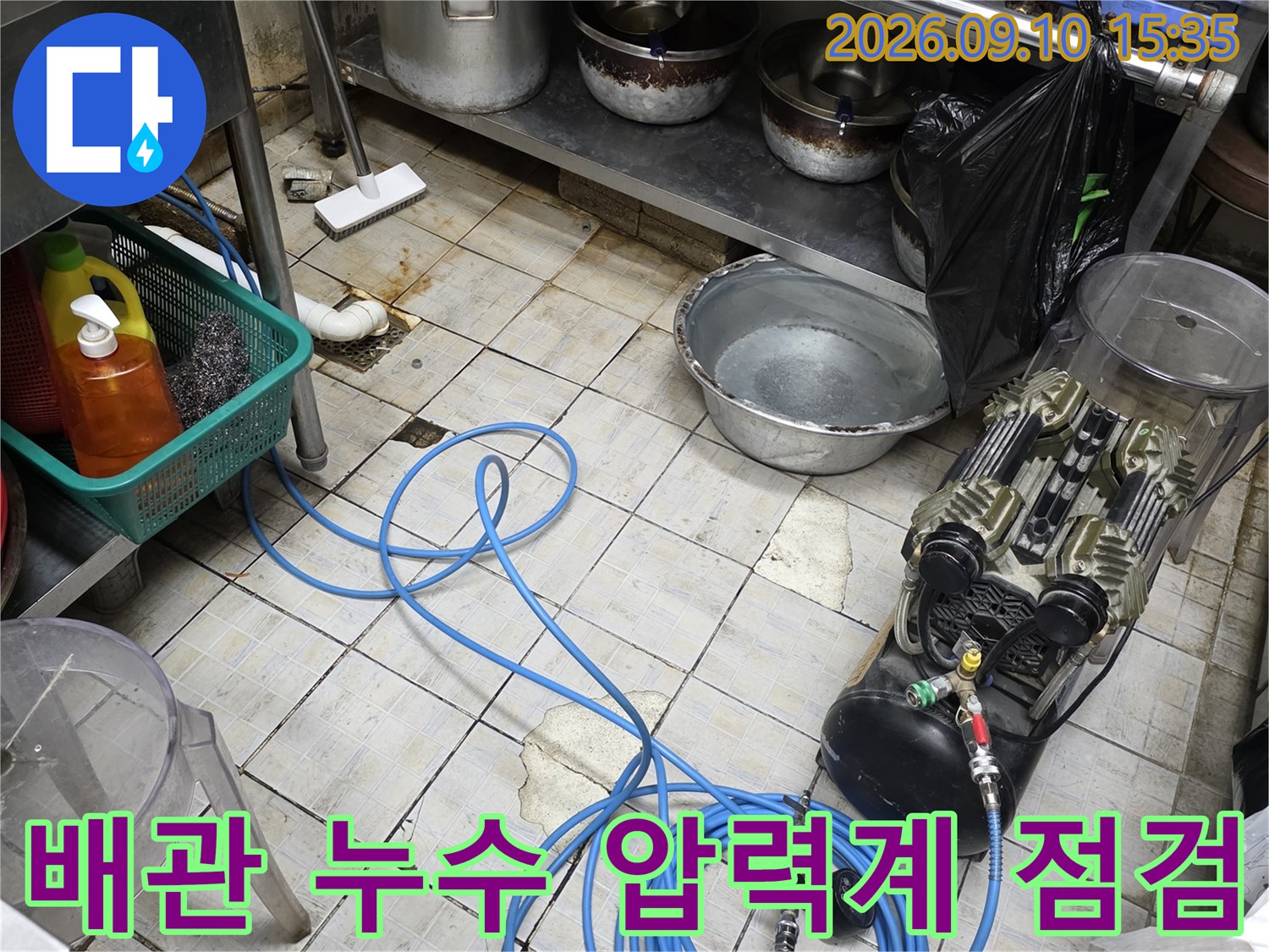 식당 주방 바닥의 배관 압력계와 연결된 파란색 호스 세트