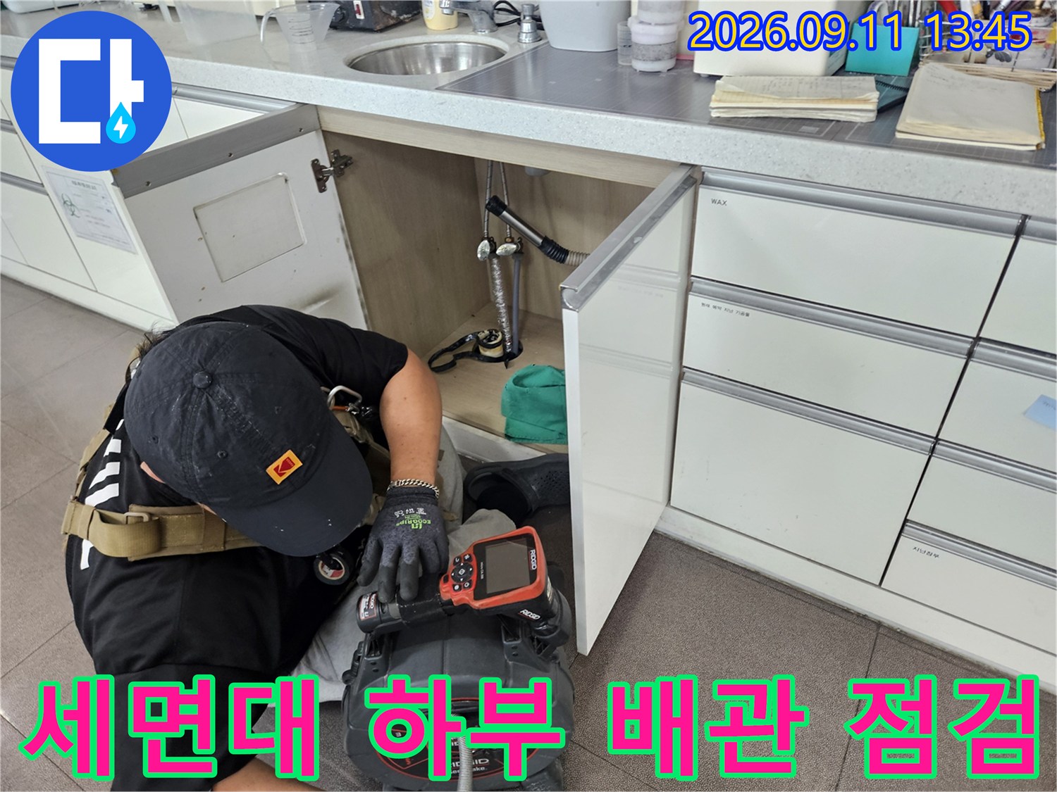 세면대 하부장 내부의 복잡한 배관 구조를 내시경과 압력계로 정밀하게 점검하고 있습니다.