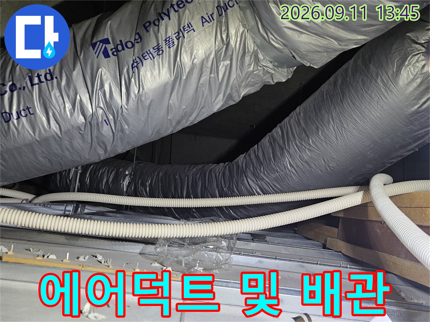 천장 내부 공간의 - 은색 에어덕트와 보온재로 감싸진 배관 배열입니다.