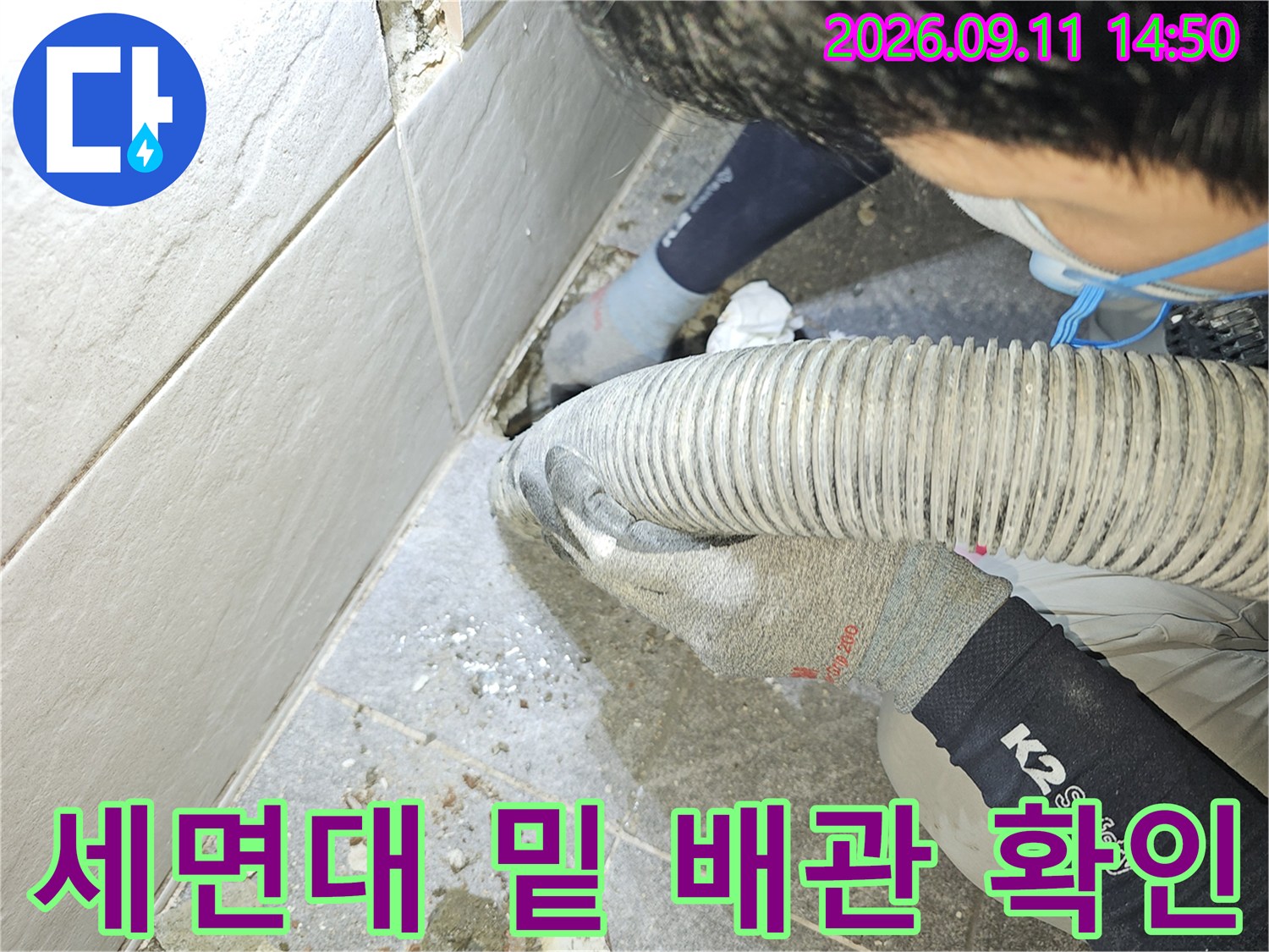 굴착된 타일 사이로 보이는 배관과 작업 중인 엔지니어의 모습입니다.