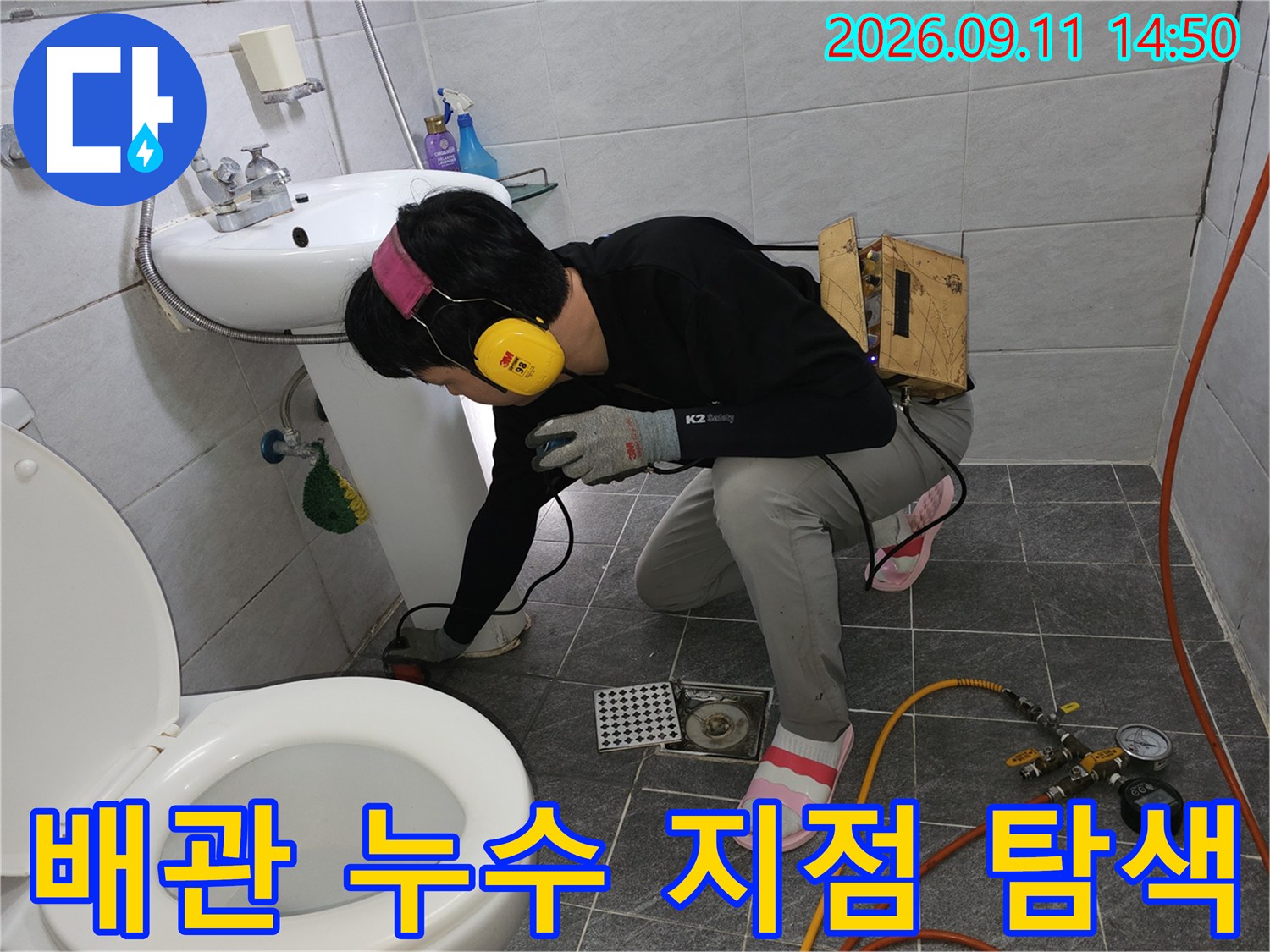세면대 아래 바닥 배관의 압력을 측정하며 누수를 찾는 엔지니어