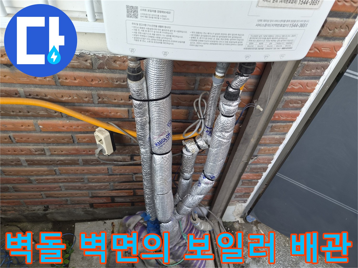 붉은 벽돌 외벽에 설치된 단열 처리된 배관 라인